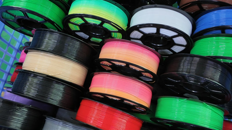 Stacks of colorful 3D printing filament spools prepared for inspection and packaging