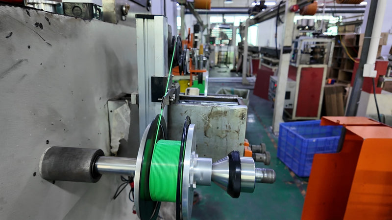 Filament winding process showing green 3D printing filament on industrial production equipment